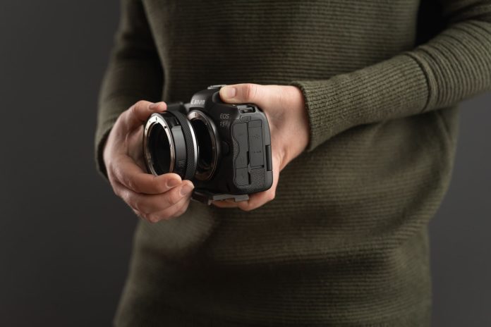 Canon EOS R5 із кріпленням для об'єктива в руках фотографа